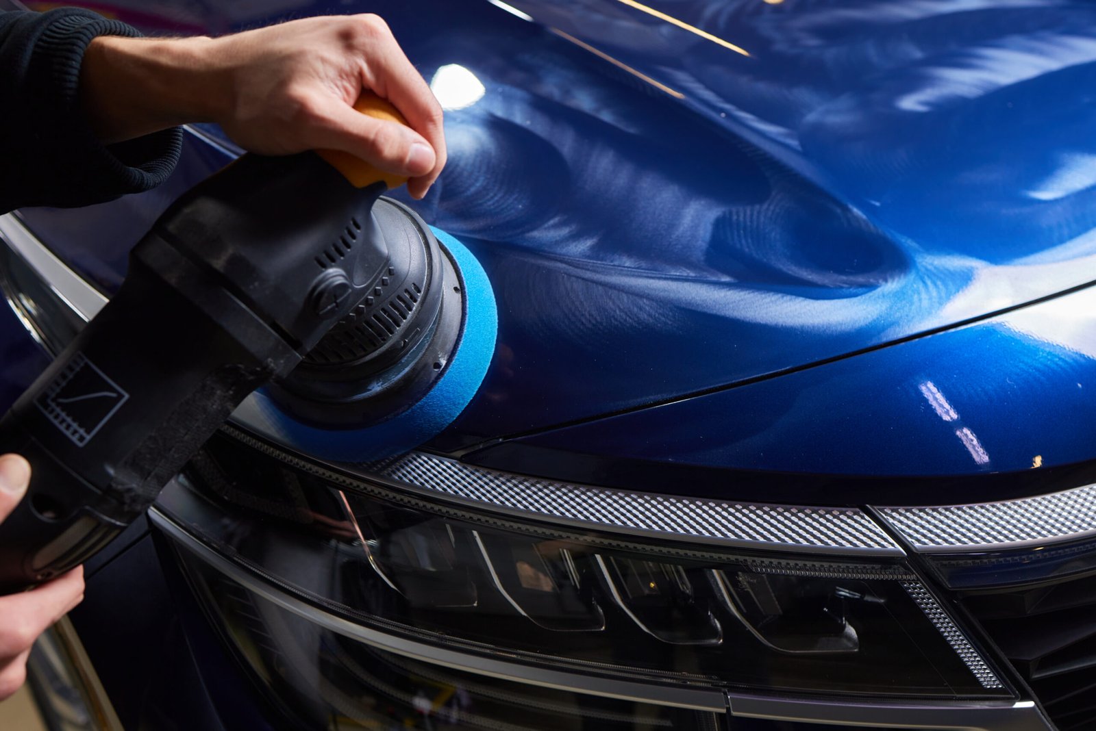man-with-orbital-polisher-car-workshop-polishing-car-closeup-1-scaled.jpg